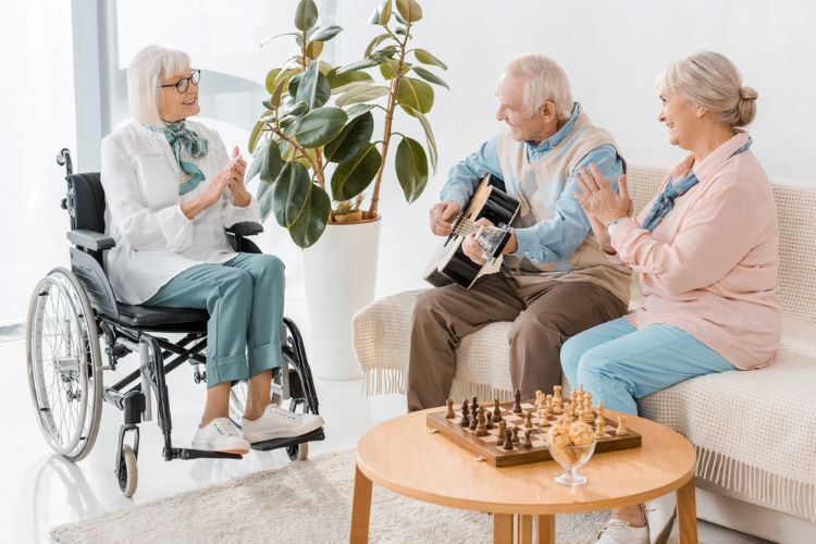 an older man playing guitar for two women